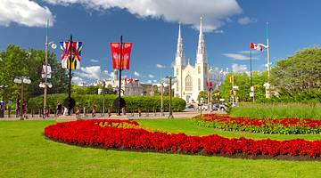 Lush garden with red flowers and flags and a building with spires in the distance