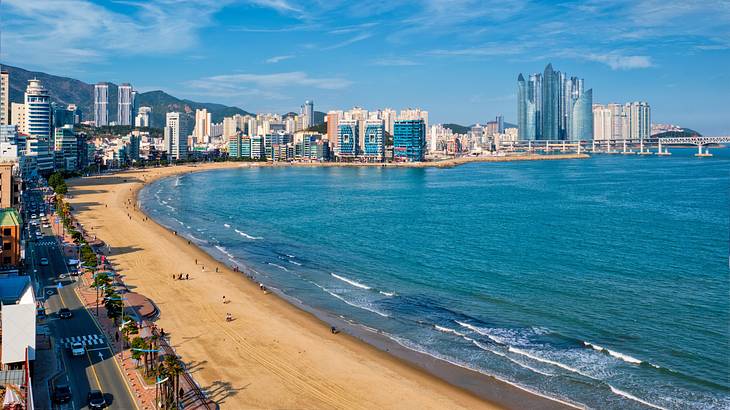 Tall skyscrapers along a golden sandy beach with small waves breaking