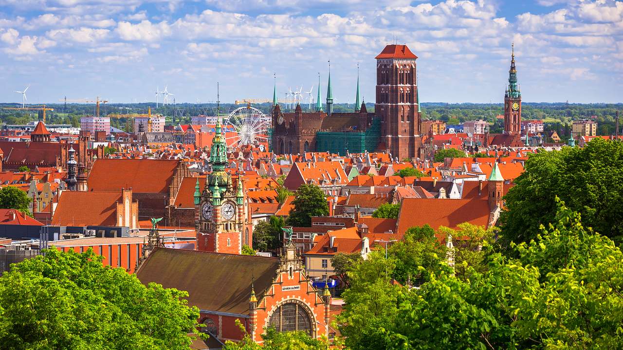 Cityscape view of buildings with red gabled roofs and spires on a sunny day