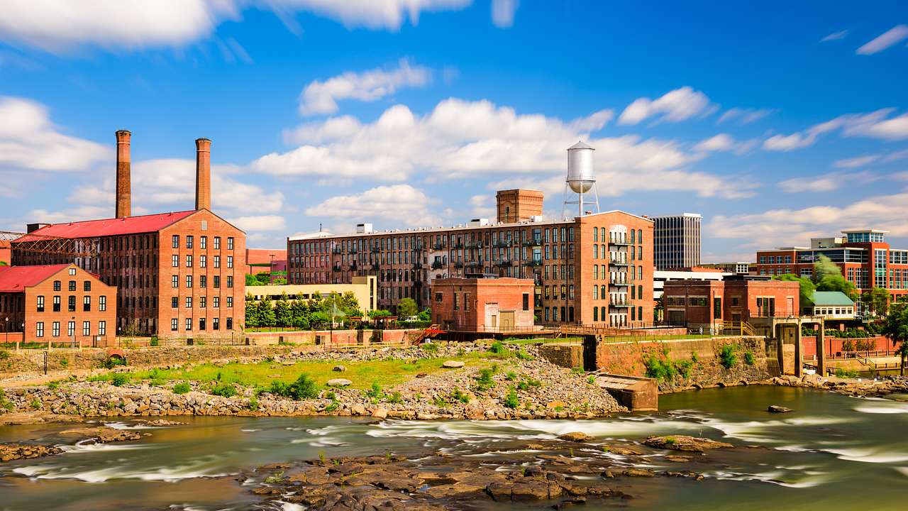 Rectangular factory-style buildings along a river bank on a nice day