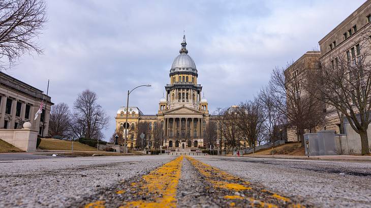 Looking up a road to an old dome-shaped government building with clouds above