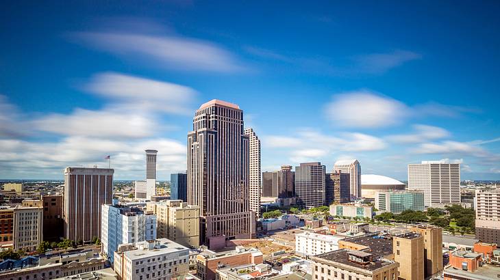 Side view of city buildings in a downtown area against blue sky with white clouds