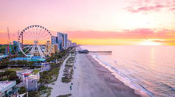 A long white sand beach with buildings and a Ferris wheel