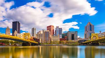 A city skyline with buildings and two yellow bridges on each side over water