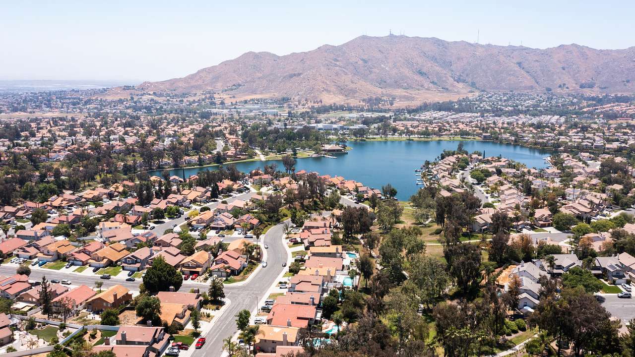 An aerial view of a suburban town with a blue lake in the middle and trees around
