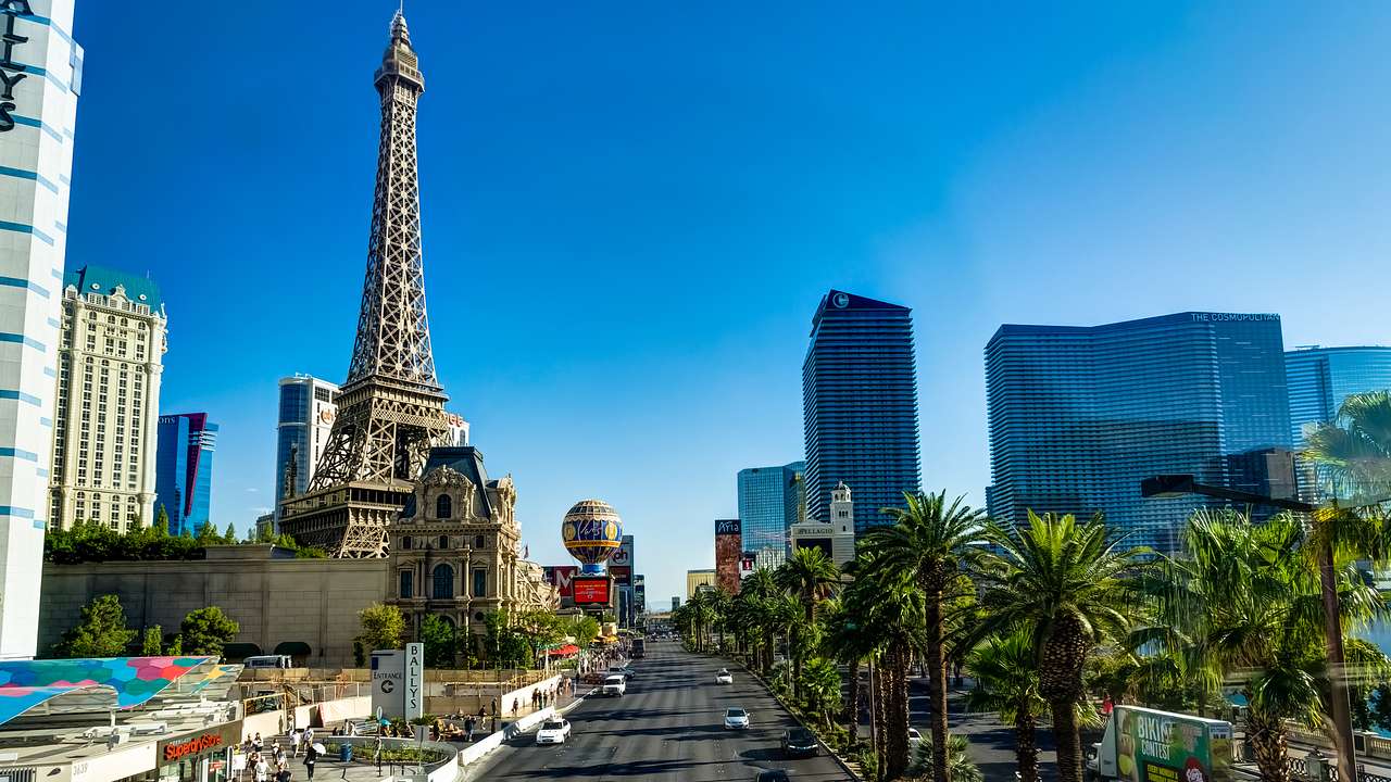 Buildings, an Eiffel Tower replica, and trees lining a road under a blue sky