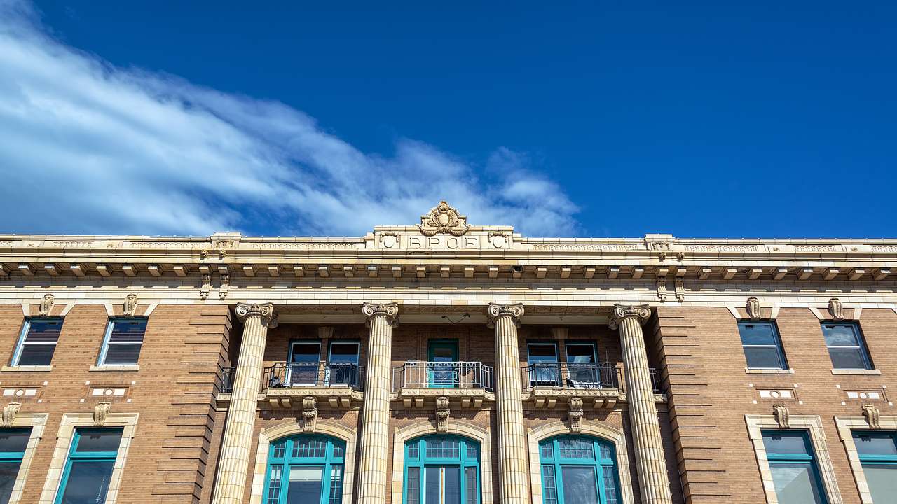 Looking up at a brick building with columns and blue sky with white clouds