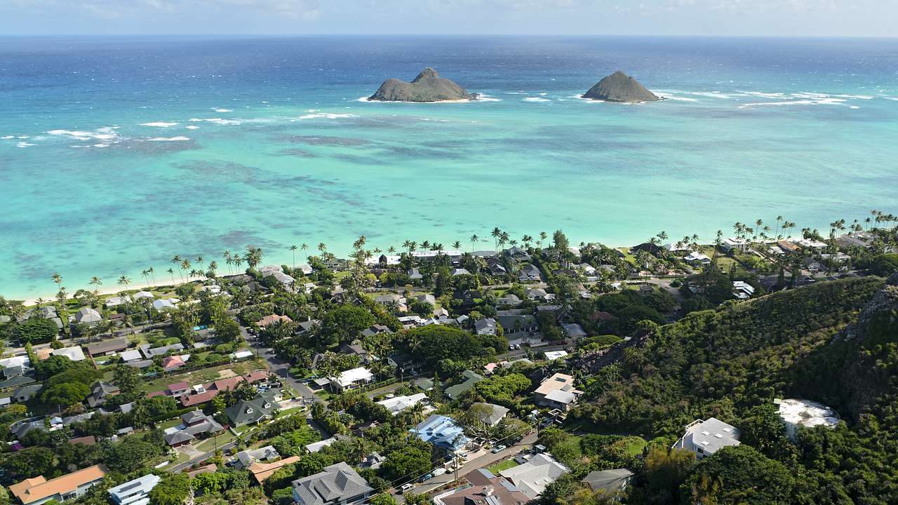 Blue and turquoise sea with two islets near a beachside town