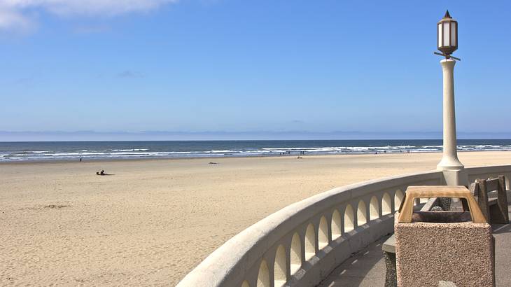 A lamppost overlooking a railing and a long stretch of sandy beach