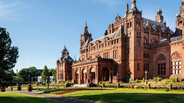 A large red brick structure with green grass in front on a clear sunny day