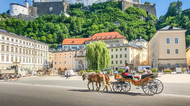 A horse pulling an antique carriage in front of an old cream colored large building