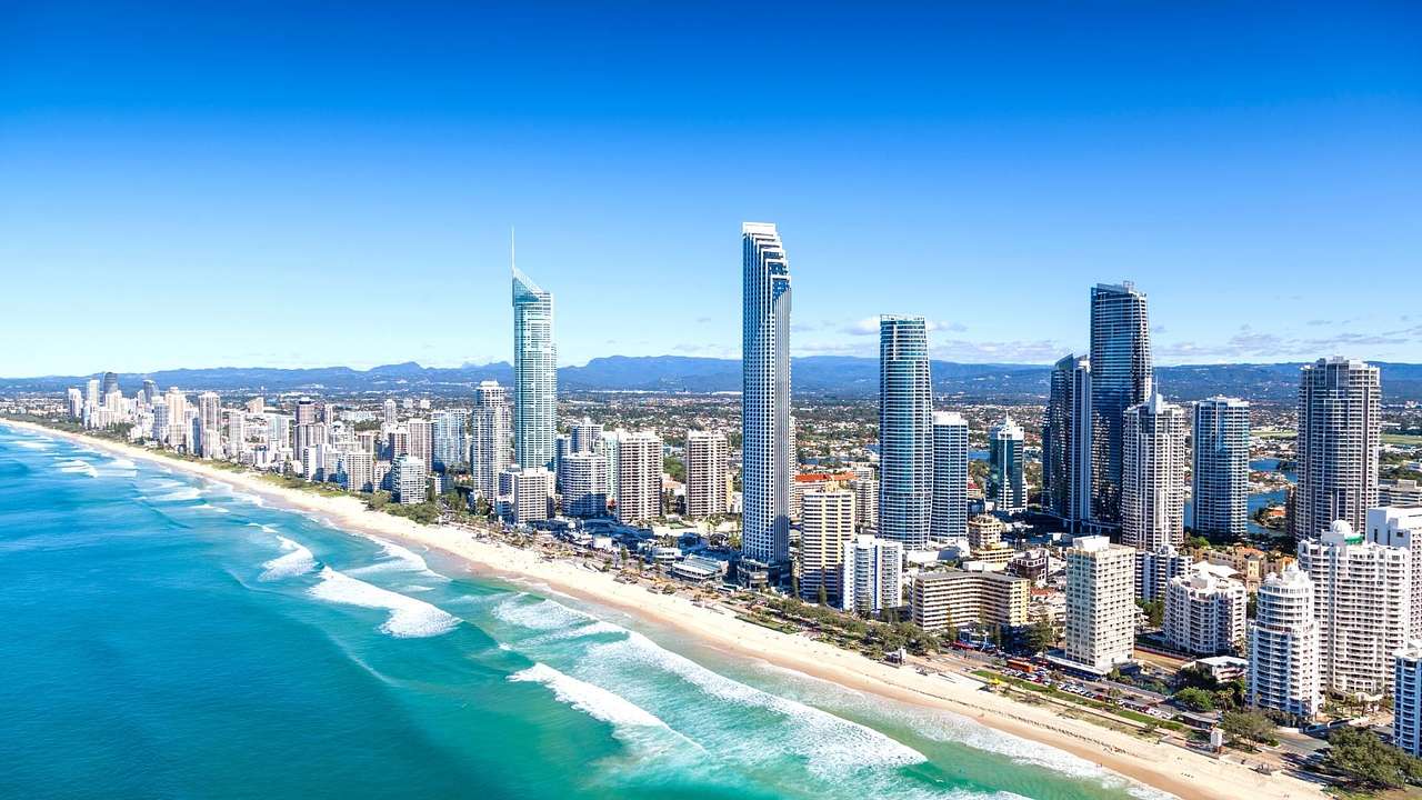 A skyline of modern tall skyscrapers along a coast with blue water