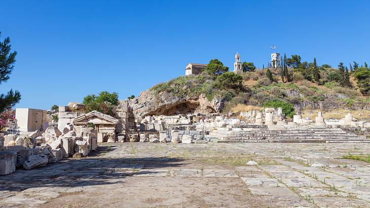 A rectangular courtyard surrounded by ruins and a hill and blue sky at the back