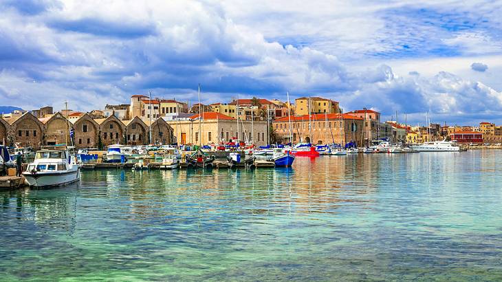 Clear blue still water with boats anchored in front of a town with brick buildings