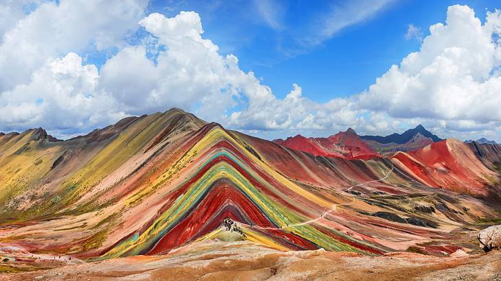 Red, yellow, green, and orange colored soils decorate the face of a tall mountain
