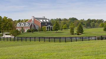 A farm-like building on the left, surrounded by green pasture and blue sky