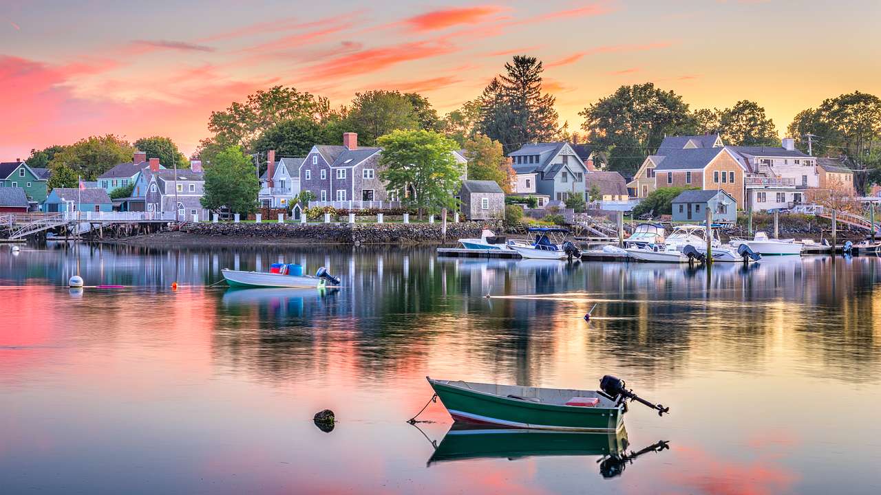 Quaint houses along a waterfront with small boats moored in front at dusk