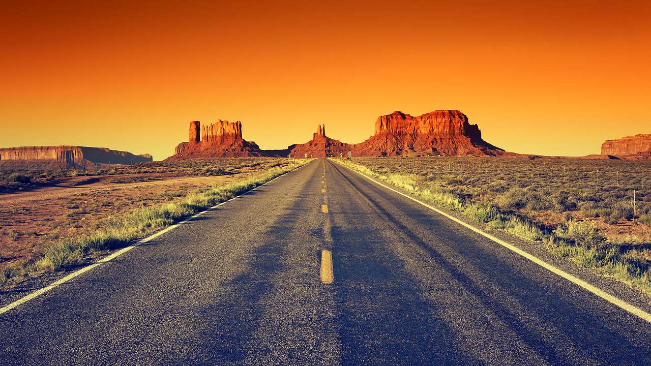 A road leading to a canyon valley at sunset with strong orange hues